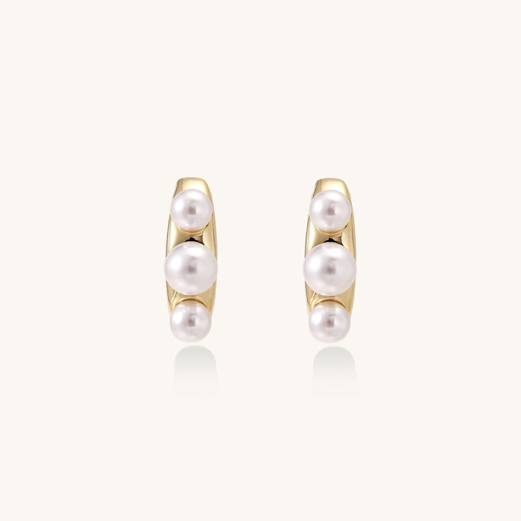 Delicate gold stud earrings with three lustrous white freshwater pearls arranged in an organic curved line.