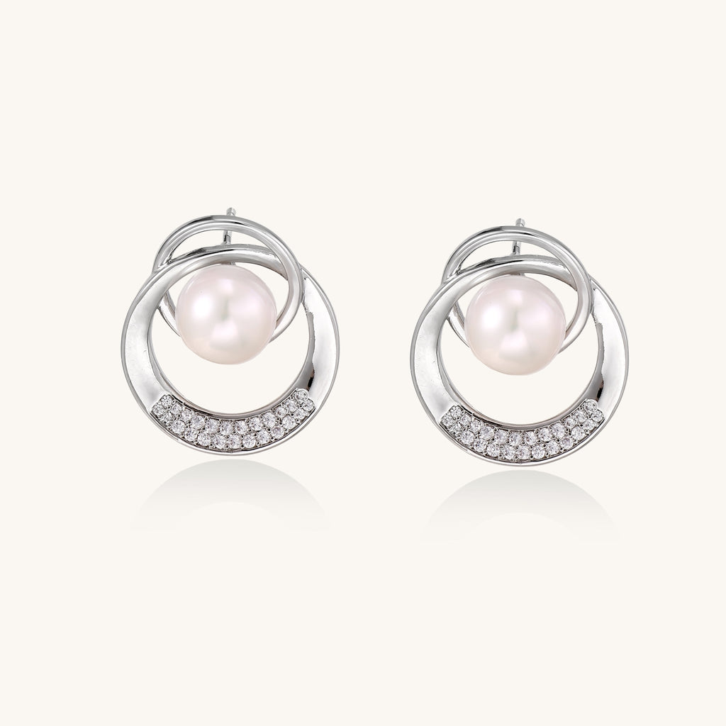 Gold-plated brass stud earrings with swirled circular design holding white freshwater pearls and small crystals