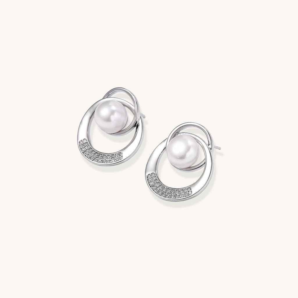 Gold-plated brass stud earrings with swirled circular design holding white freshwater pearls and small crystals