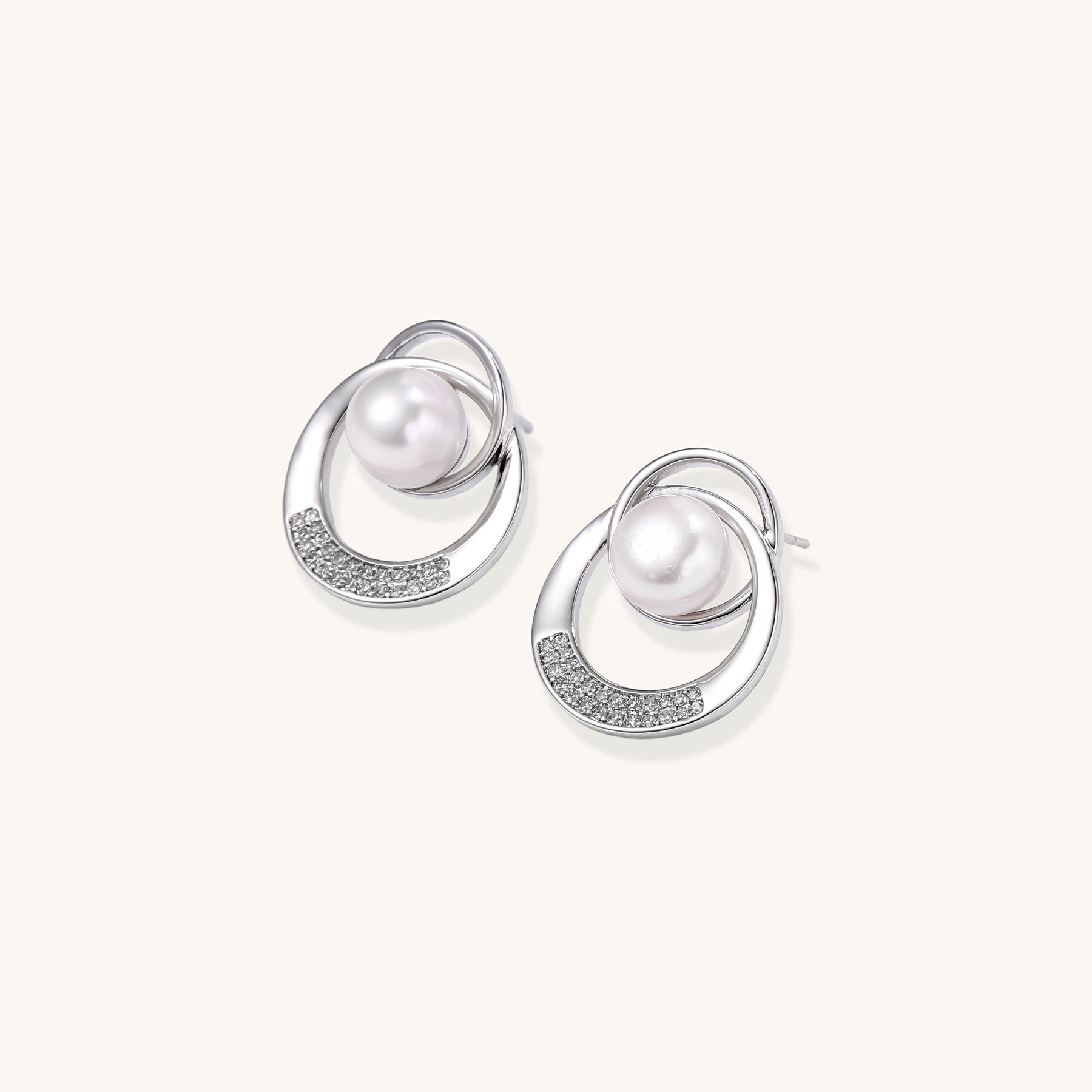Gold-plated brass stud earrings with swirled circular design holding white freshwater pearls and small crystals