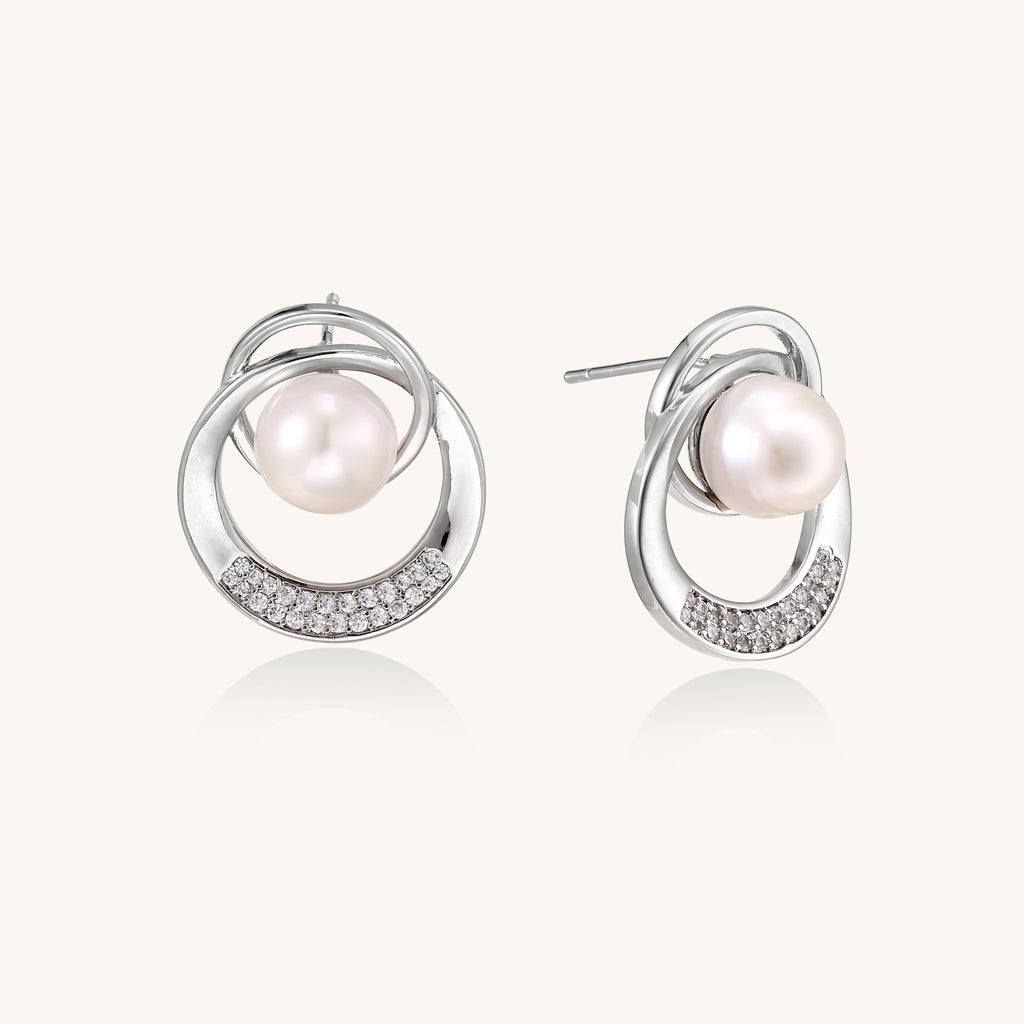 Gold-plated brass stud earrings with swirled circular design holding white freshwater pearls and small crystals