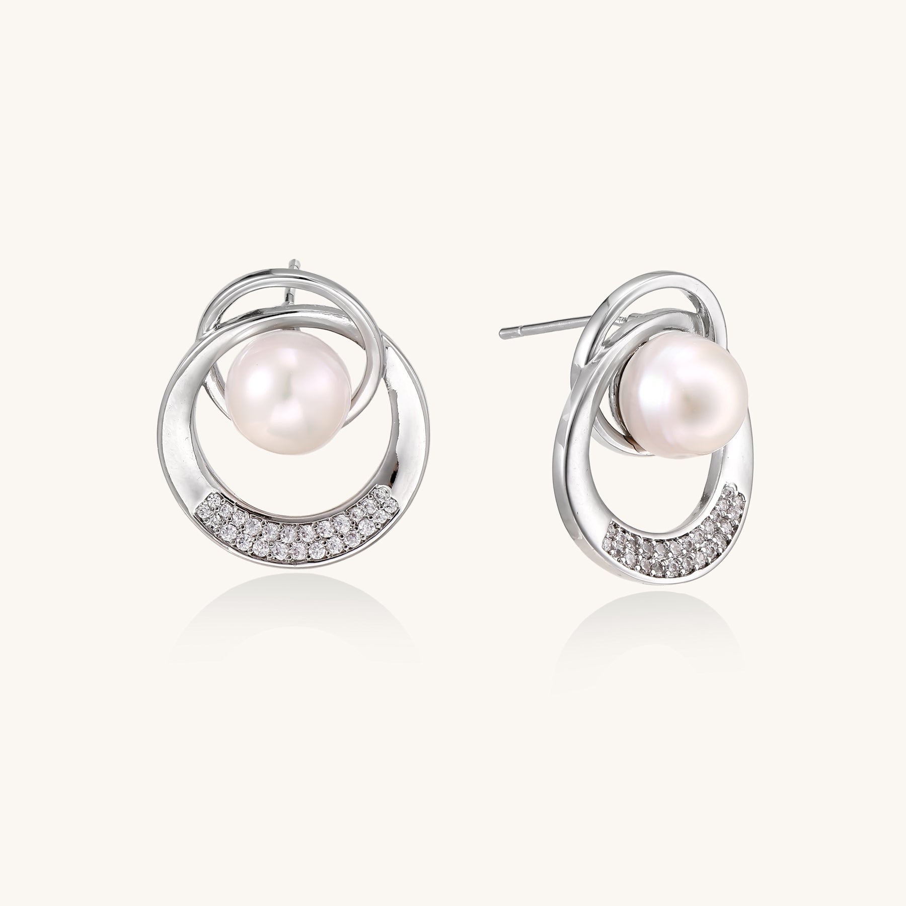Gold-plated brass stud earrings with swirled circular design holding white freshwater pearls and small crystals