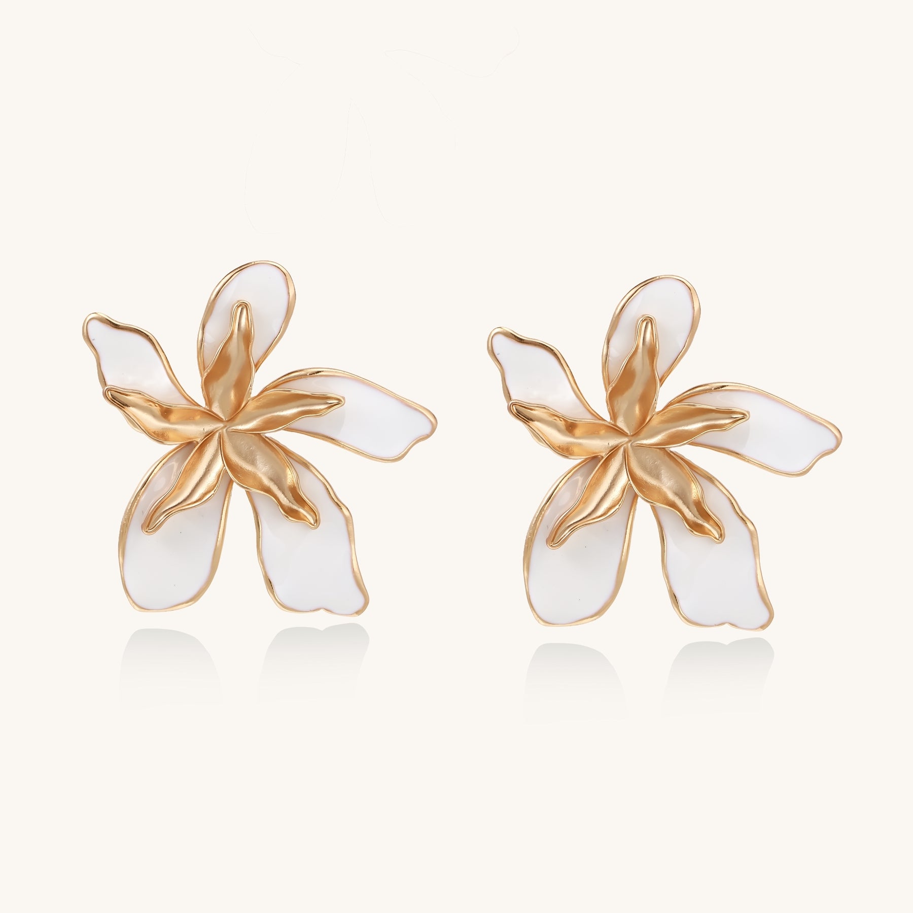 Large floral stud earrings with gold-plated brass petals and white enamel centers on neutral background