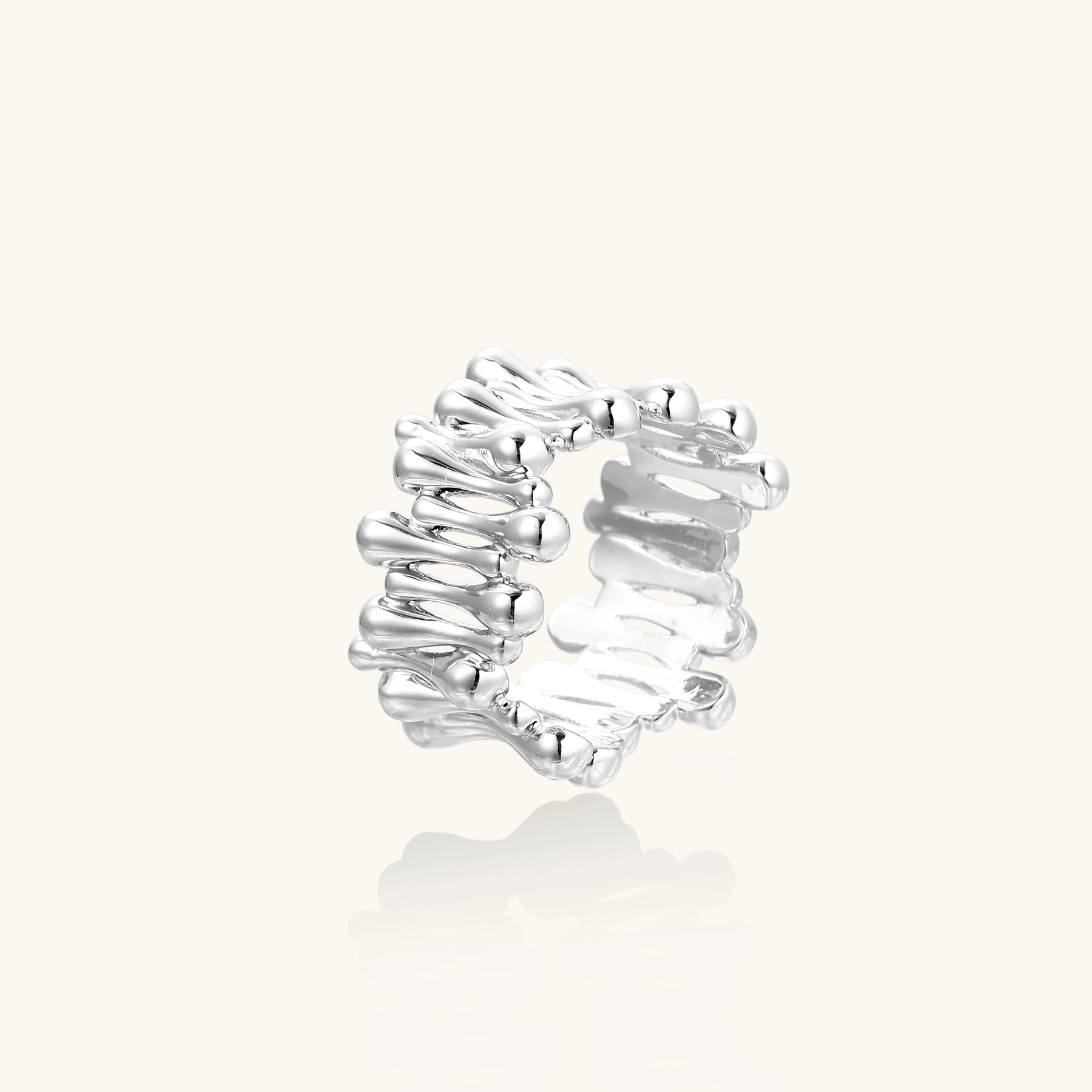 Close-up of an artistic gold-plated brass ring with multiple twisted bands creating a sculptural flowing design