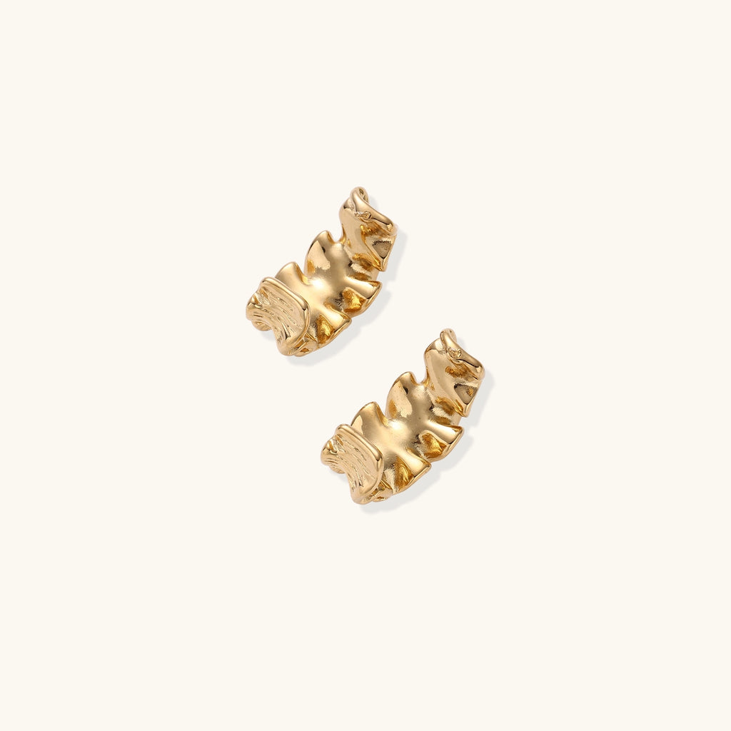 Close-up of dimensional gold-plated hoop earrings with rippled wave texture against white background.