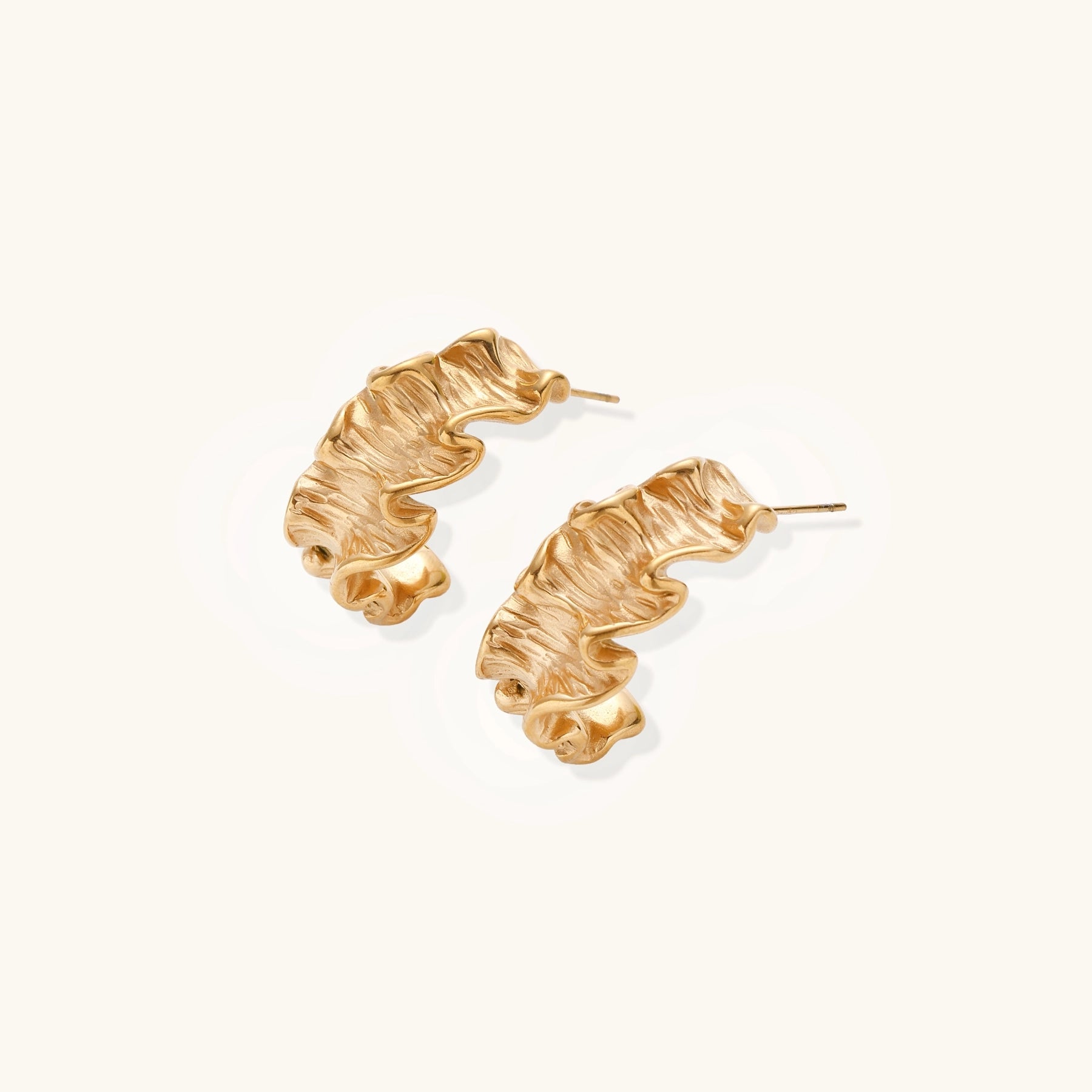 Textured gold-plated hoop earrings with wavy sculptural ridges displayed against a neutral background.