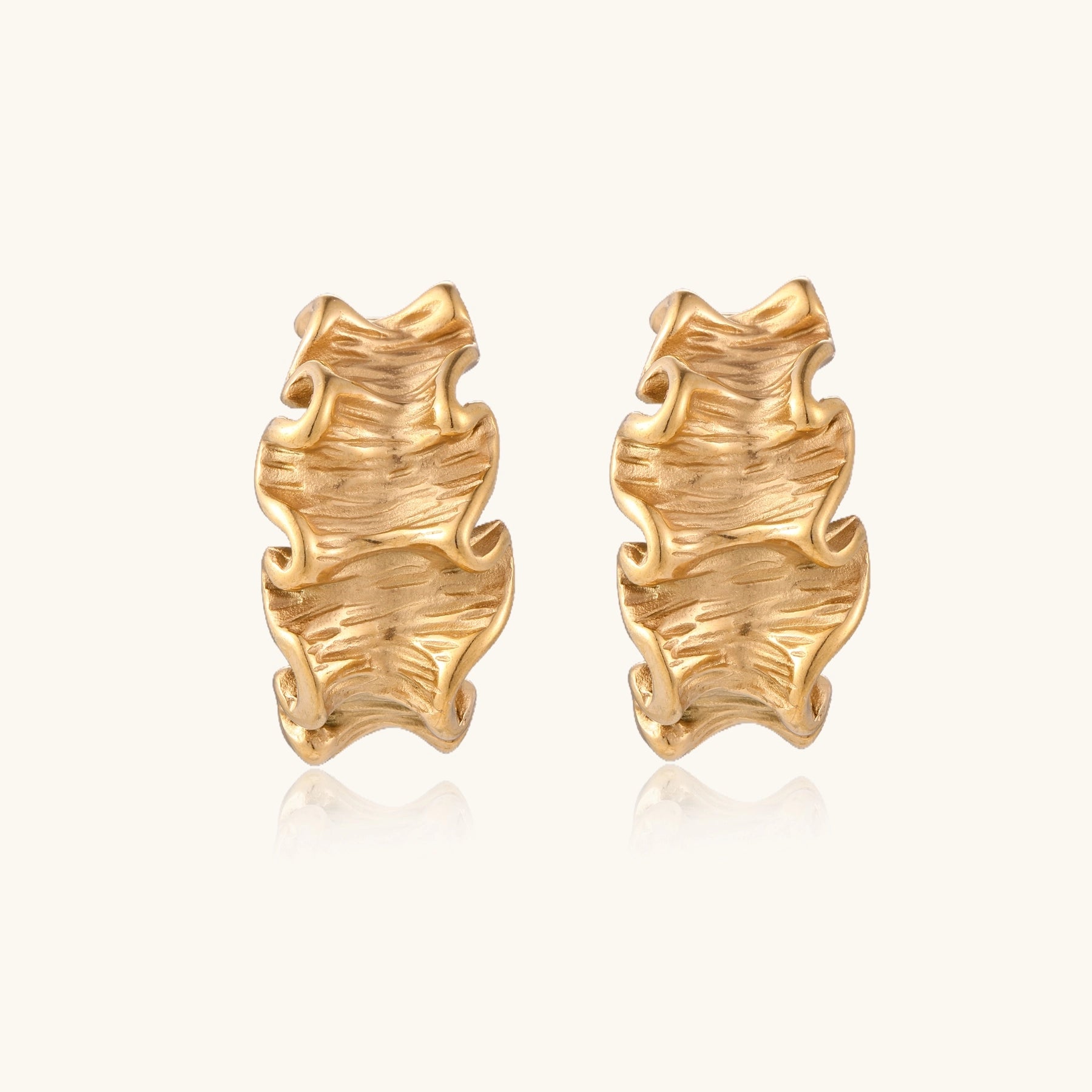 Textured gold-plated hoop earrings with wavy sculptural ridges displayed against a neutral background.